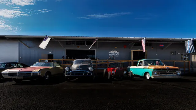 Classic cars parked in front of Ashtown's taproom, flags along the deck